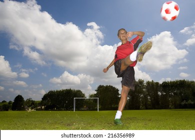 Teenage Girl In Uniform Kicking Soccer Ball