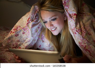 Teenage Girl Using Digital Tablet In Bed At Night