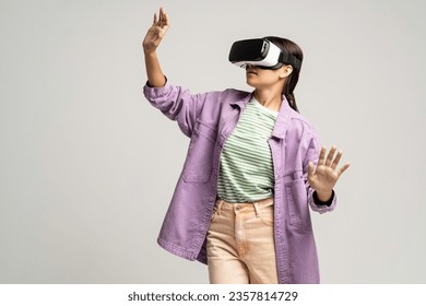 Teenage girl using virtual reality headset. Teenager testing vr grasses isolated on studio gray background. VR, future technology, gadgets, online gaming, training, exploring cyberspace, video game - Powered by Shutterstock