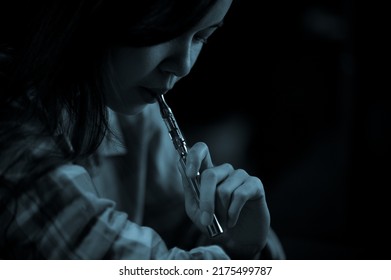 Teenage girl vaporize cannabis through a vaporizer containing cannabis oil in a tube after electrical heating