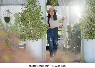 A Teenage Girl Wearing A Denim Bib Holding A Paper Sign Stands In Front Of The Door Of A Tree Planting House With A Smiling Face.