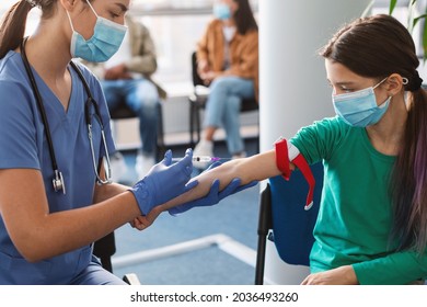 Teenage Girl Wearing Face Mask And Medical Tourniquet On Arm While Nurse Taking Blood Sample For Analysis. Laboratory Assistant Giving Injection Into Vein. Concept Of Healthcare And Medicine.