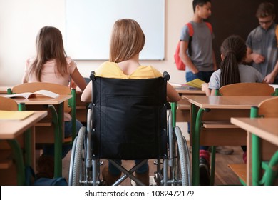 Teenage girl in wheelchair with classmates at school