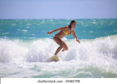 teenage girl in a yellow bikini surfing in Hawaii