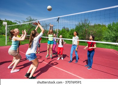 Teenage girls and boy play together volleyball