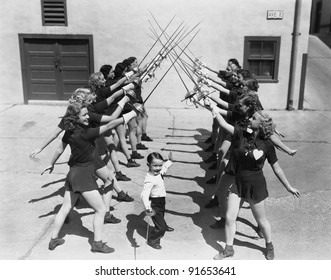 Teenage girls and little boy fencing