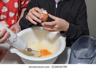 Teenage girls make dough. Large bowl with flour and breaking eggs, kitchen mixer. close-up of hands - Powered by Shutterstock