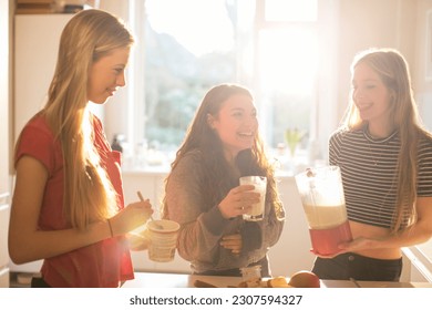 Teenage girls making smoothie in sunny kitchen - Powered by Shutterstock