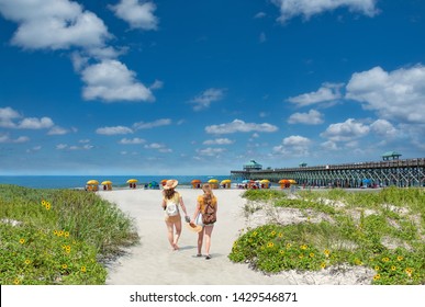 Teenage girls relaxing on  the beautiful beach, People enjoying summer vacation by the ocean.Girls walking on the beach.  Cloudy sky and pier in the background. Folly Beach, South Carolina USA.  - Powered by Shutterstock