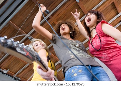 Teenage Girls Singing And Playing Guitar In Band In Garage