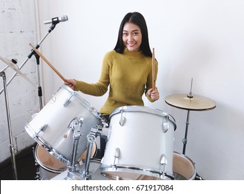 Teenage girls smiling while playing drum, happiness and enjoying music concepts.