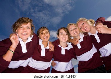 Teenage girls in sports uniforms discussing strategy for the game and looking at the camera. - Powered by Shutterstock