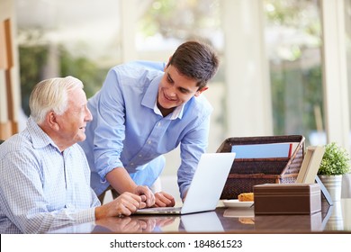 Teenage Grandson Helping Grandfather With Laptop