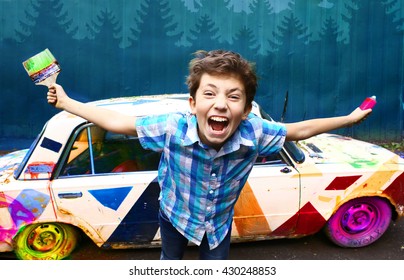 teenage handsome boy with brush and graffiti spray on the old painted retro car background closeup portrait on the blue wall background