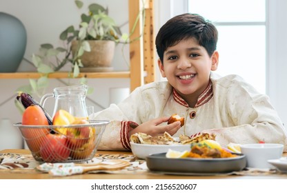 Teenage handsome Indian boy wearing traditional clothes, smiling with happiness at table in kitchen at home, having delicious meal breakfast, lunch or dinner. Family, Education and Lifestyle concept - Powered by Shutterstock