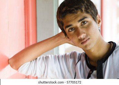 Teenage Indian Boy Resting His Head in Hand Leaning Against a Doorway