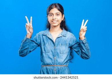 teenage indian girl hand gesturing for peace sign or v-sign or victory sign