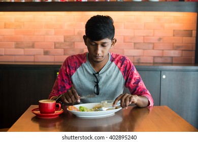 Teenage Indian Male Eating At Cafe