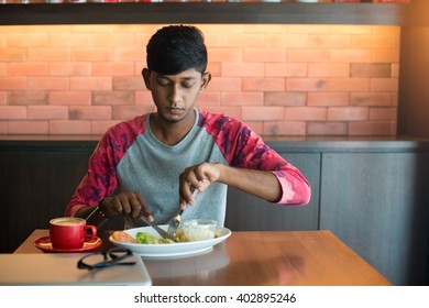 Teenage Indian Male Eating At Cafe