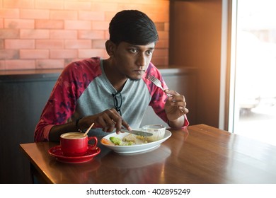 Teenage Indian Male Eating At Cafe