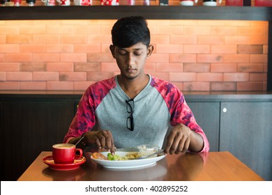 Teenage Indian Male Eating At Cafe