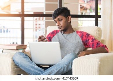 teenage indian male using laptop and phone
