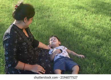 Teenage Indian Mother Spending Time With Her Little Son At The Park . Happy Little Image. Indian Boy Looking His Mother. Outdoors Image.