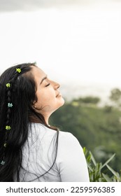 teenage Latin girl, with her head raised to the sky, breathing the fresh air - Shutterstock ID 2259596385