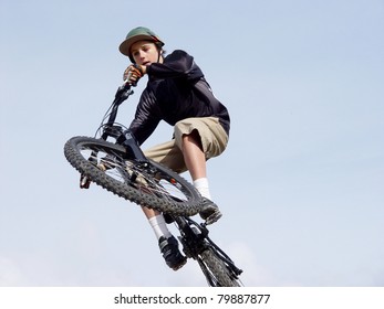 Teenage Male Doing High Jump On A Bmx Bike, Blue Sky Background