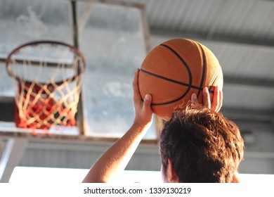 Teenage Man Shooting A Hoop On A Basketball Court.