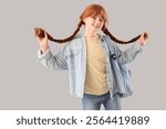 Teenage redhead girl with pigtails and backpack on light background