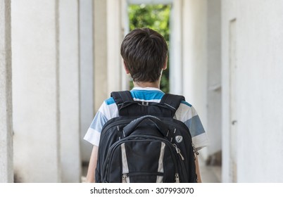 Teenage School Boy With A Backpack On His Back Walking To School. Back View