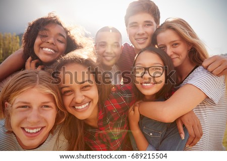 Teenage school friends smiling to camera, close up
