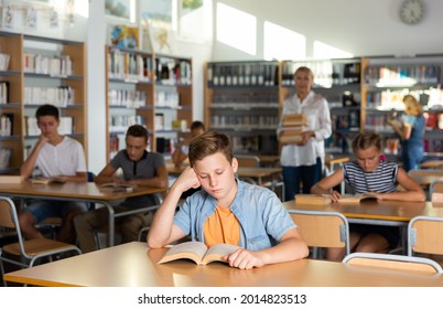 Teenage schoolers reading and writing in college library - Powered by Shutterstock