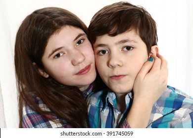 teenage siblings brother and sister with long brown dark hair in scottish shirt hug kiss close up portrait isolated on white