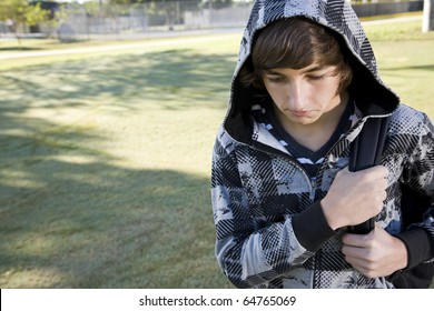 Teenage student (15 years) carrying bookbag on shoulder, looking down with serious expression