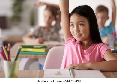 Teenage Student Raising Hand In Classroom 