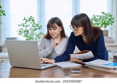 Teenage student studying at desk with computer, trainer mentor helping teaching - Powered by Shutterstock