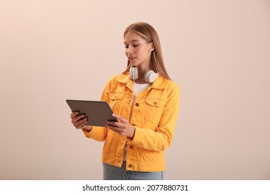 Teenage student with tablet and headphones on beige background - Powered by Shutterstock