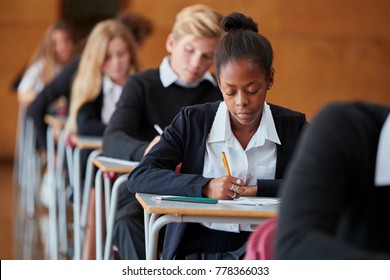 Teenage Students In Uniform Sitting Examination In School Hall