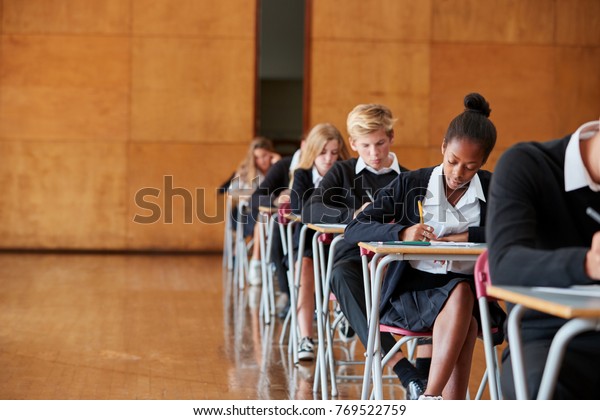 Teenage Students In Uniform Sitting Examination In
School Hall