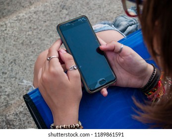 Una adolescente con un teléfono inteligente en las escaleras de un edificio histórico