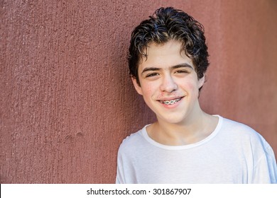 teenager with acne skin smiling while showing braces on red grunge wall