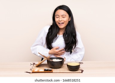 Teenager Asian Girl Eating Asian Food Isolated On Beige Background Smiling A Lot