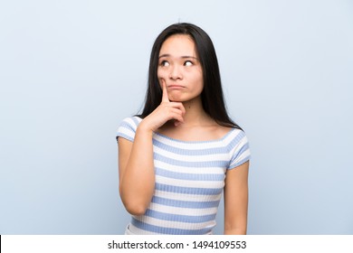 Teenager asian girl over isolated blue background thinking an idea