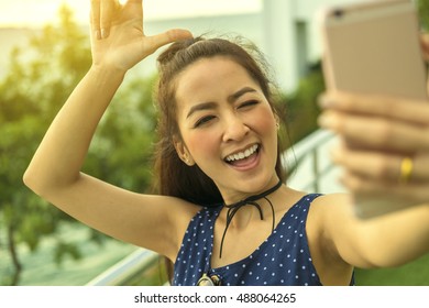 Teenager Asian Girl Waving To The Camera During A Smart Phone Video Call In Vacations With The Sea In The Background