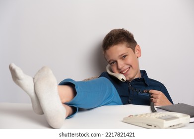 Teenager With Bad Upbringing Talking To The Phone Putting His Feet On The Table