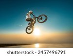 A teenager BMX Racing Rider performs tricks in a skate park on a pump track.