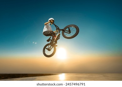 A teenager BMX Racing Rider performs tricks in a skate park on a pump track. - Powered by Shutterstock