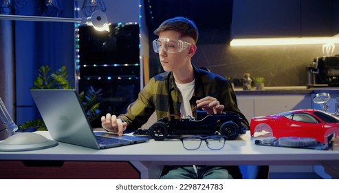 Teenager boy according to a video he watches on his laptop and tighten the nut with a screwdriver to assemble car toy, creating electronic AI technology workshop school lesson. Hobbies for advanced - Powered by Shutterstock